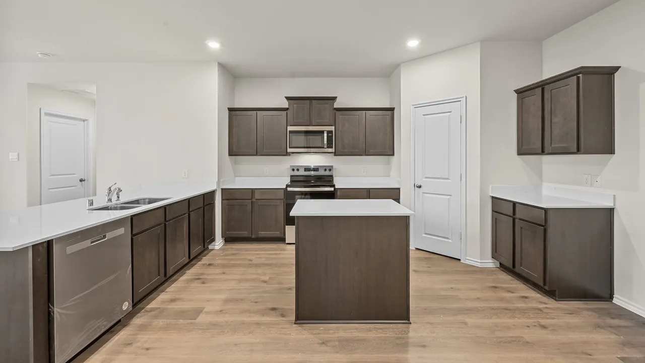 Kitchen featuring wood-finish flooring, a central island, dark wood cabinetry, white countertops, and stainless steel appliances