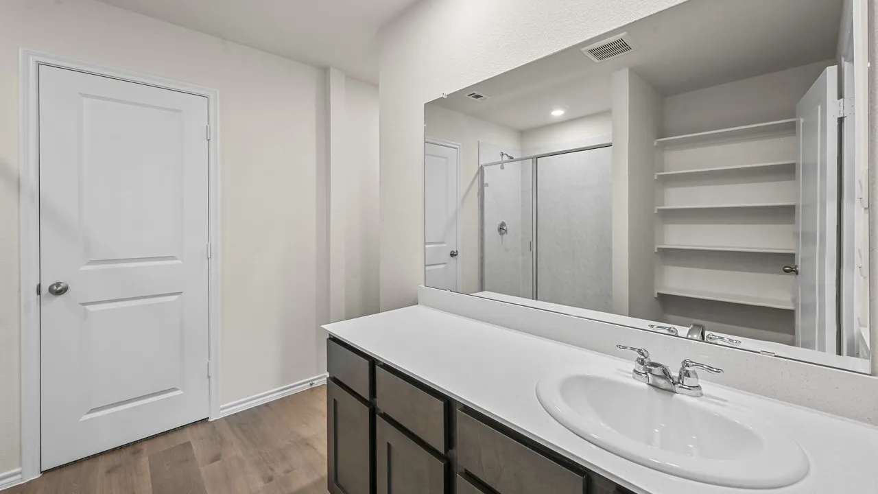 Bathroom vanity featuring a white oval undermount sink, chrome faucet, and dark wood-finish cabinetry