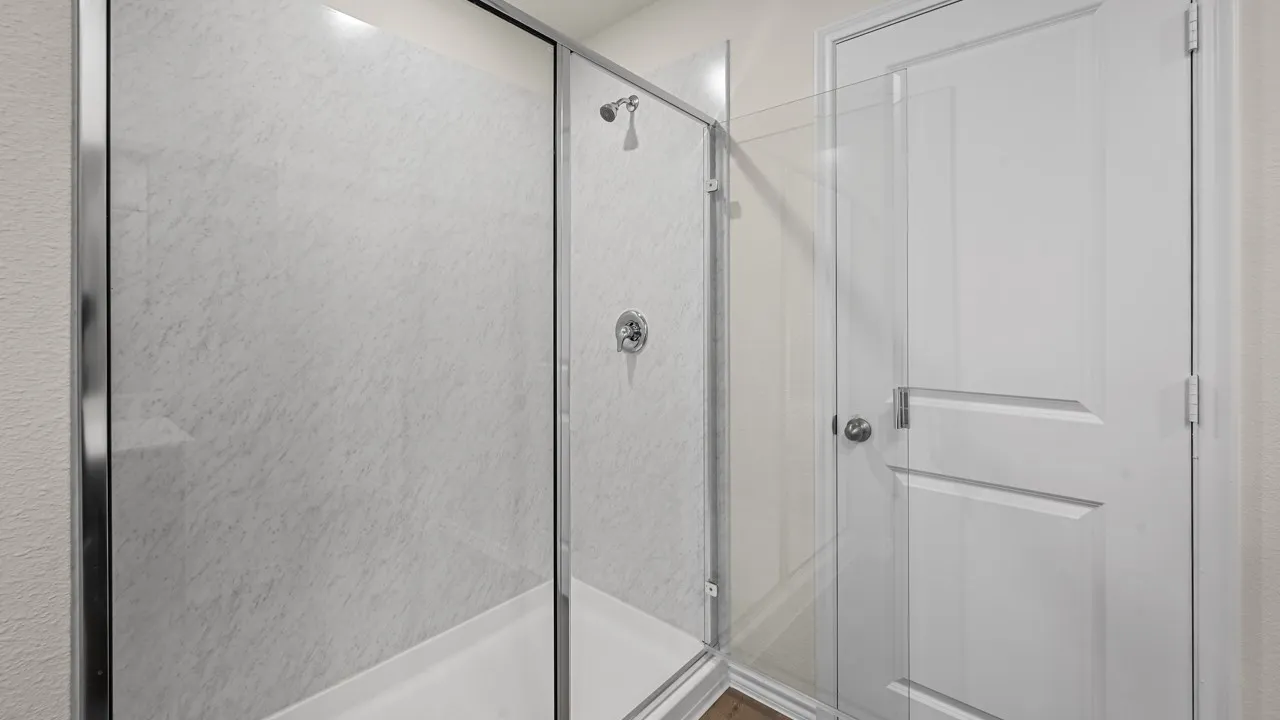 Glass-enclosed shower with white tiled walls and a built-in shelf