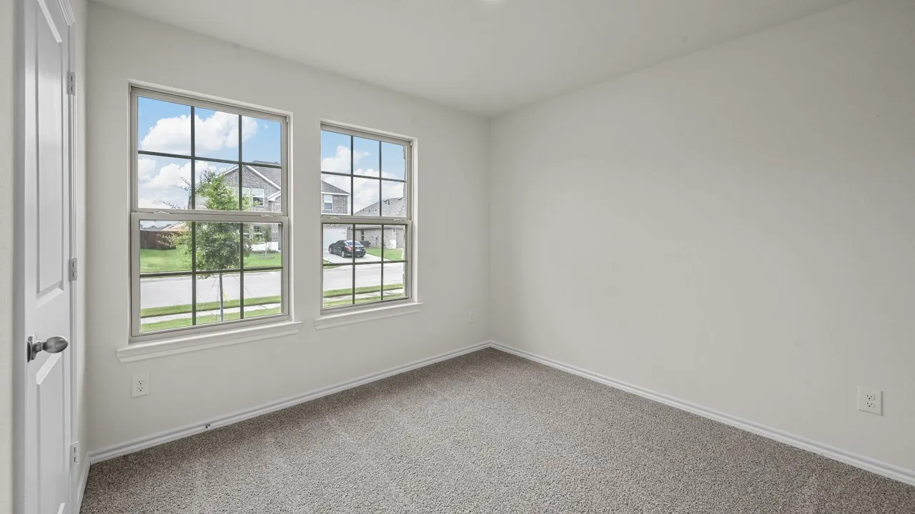 Bright interior space featuring two large windows with grid muntins, neutral gray carpet, white walls, and white trim