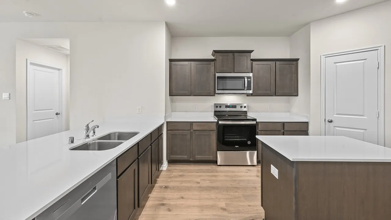 Kitchen featuring wood-finish flooring, dark wood cabinetry, white countertops, stainless steel appliances, and a central island