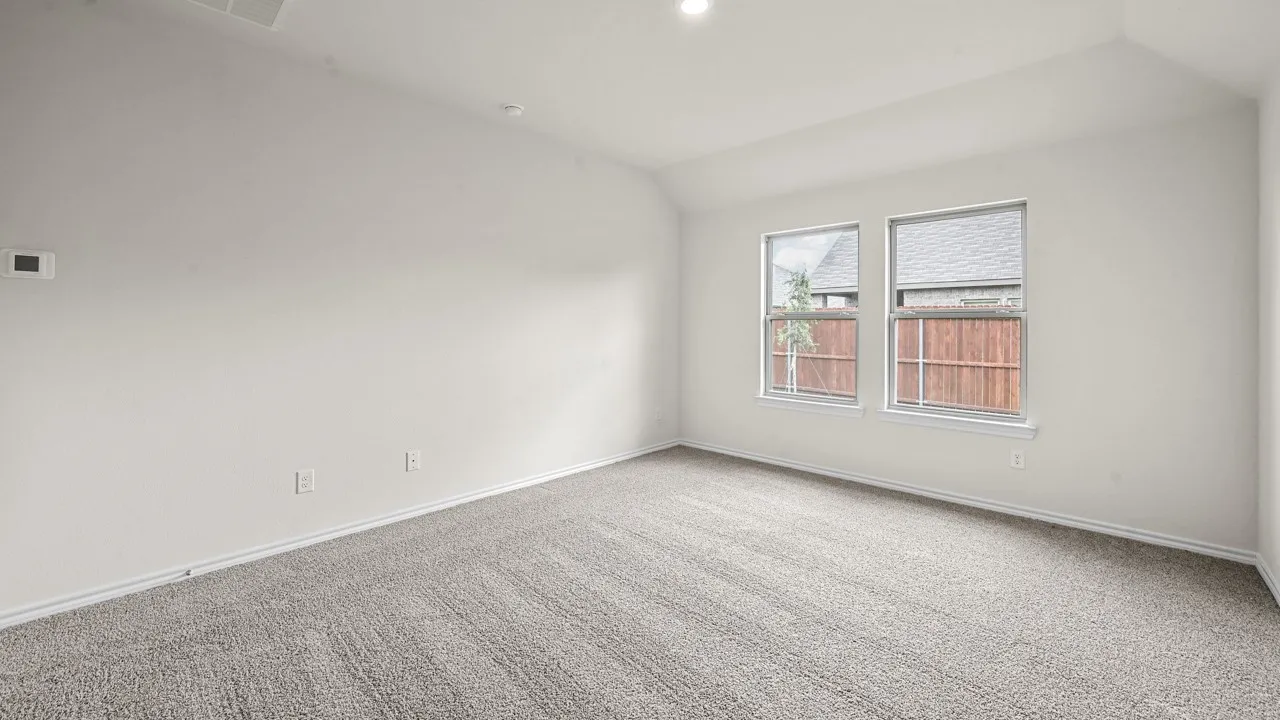 Spacious room featuring neutral carpeting, two windows, vaulted ceiling, and recessed lighting