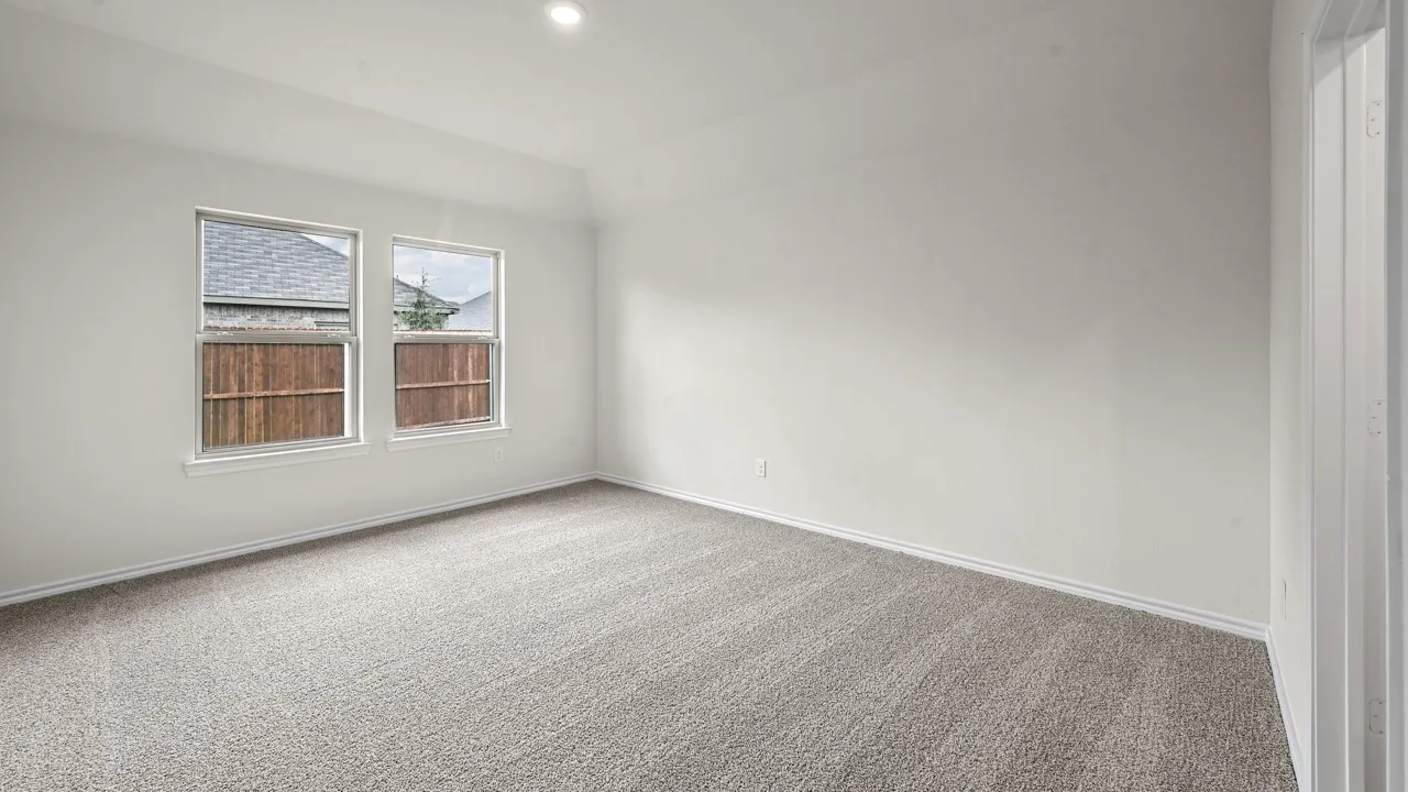 Spacious room featuring neutral carpeting, light-toned walls, and recessed lighting