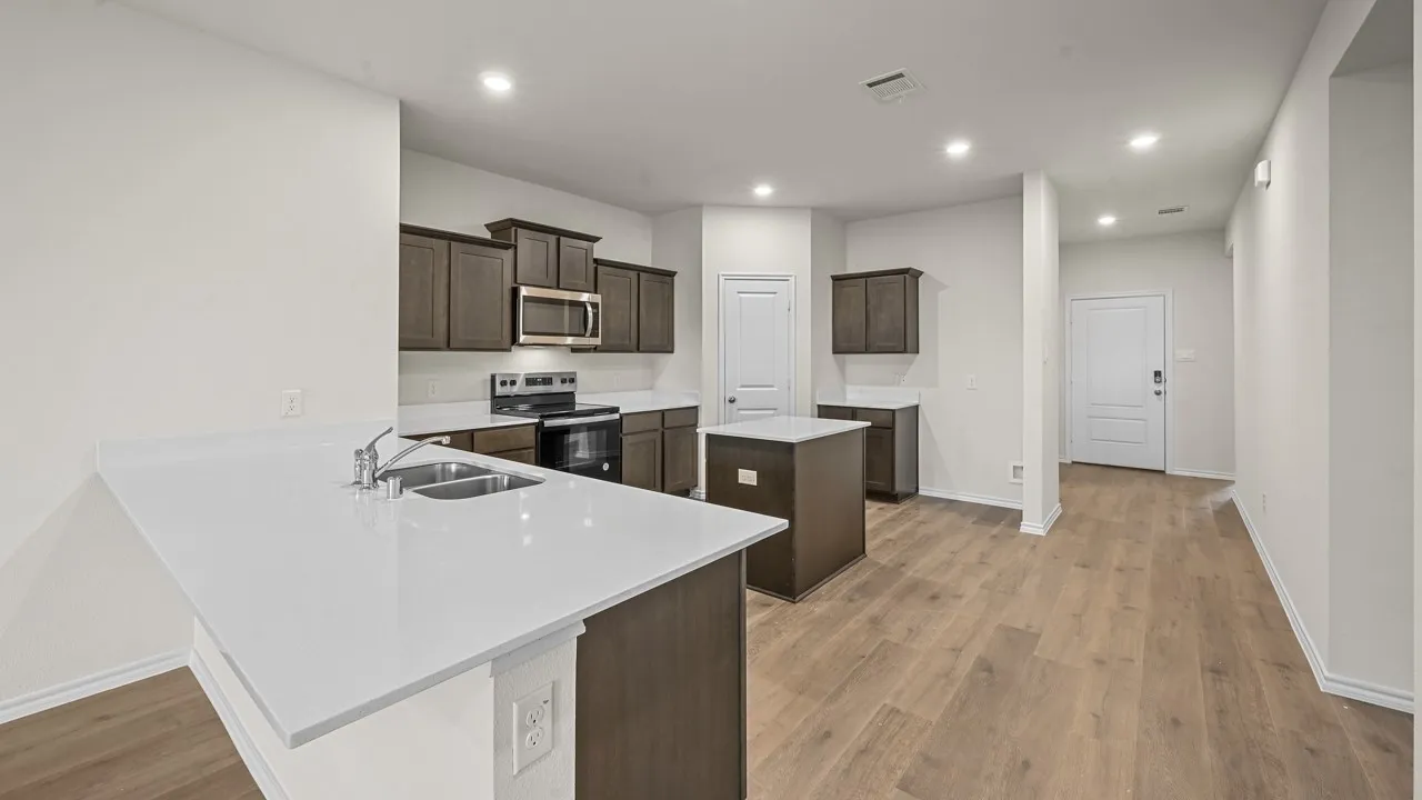 Modern kitchen featuring white countertops, stainless steel appliances, dark wood cabinetry, and wood-finish flooring