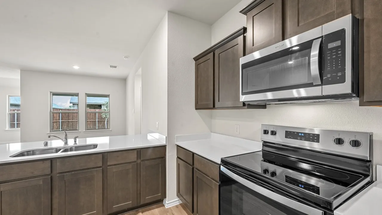Kitchen featuring wood-finish cabinetry, white countertops, stainless steel appliances, and a double basin sink
