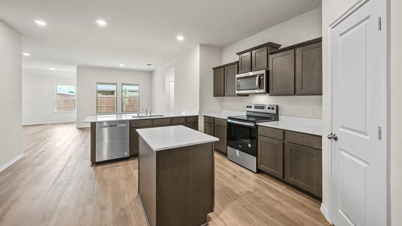 Modern kitchen featuring dark wood-finish cabinetry, light countertops, and stainless steel appliances