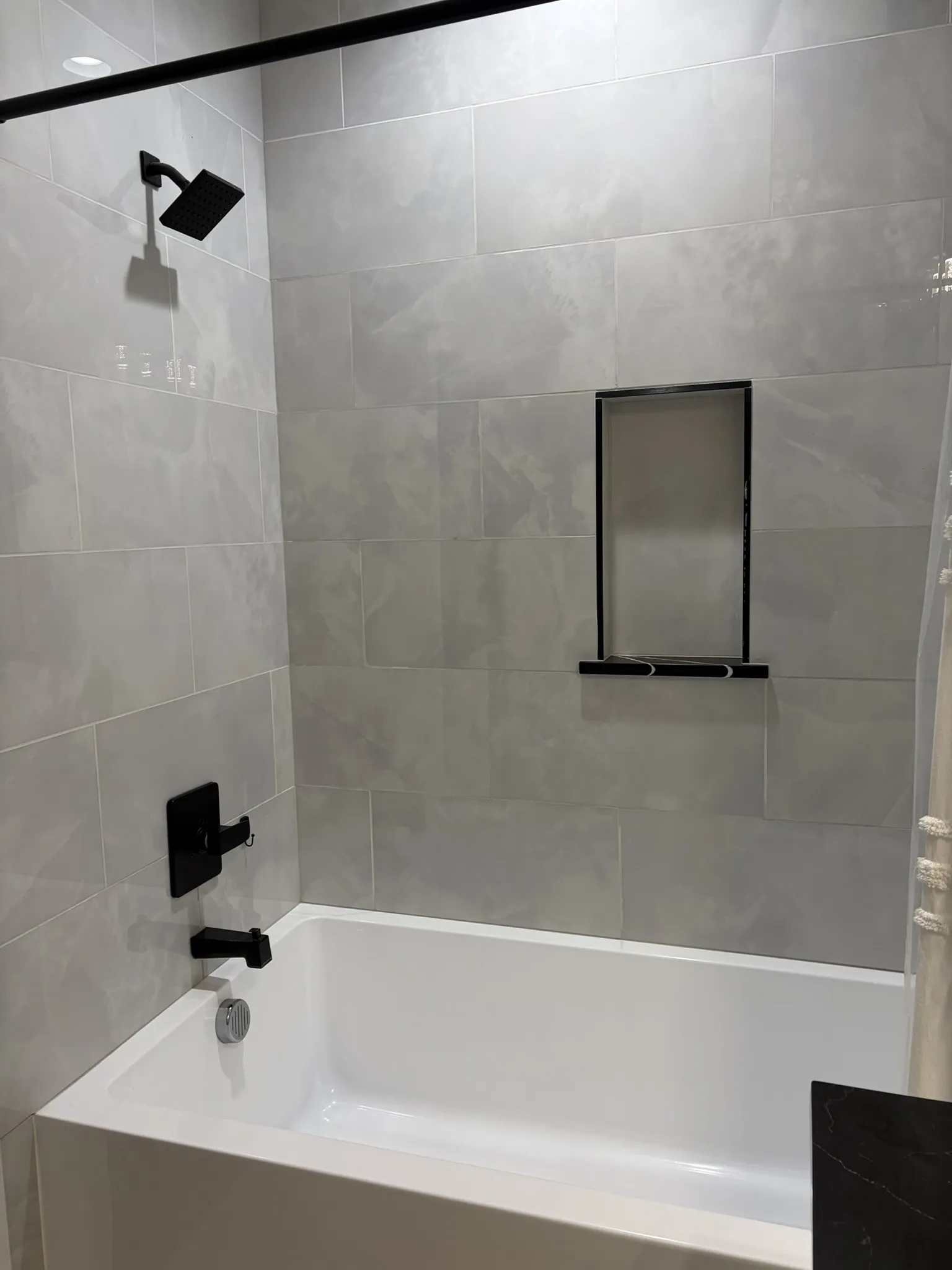 Bathtub with light gray large format tile surround