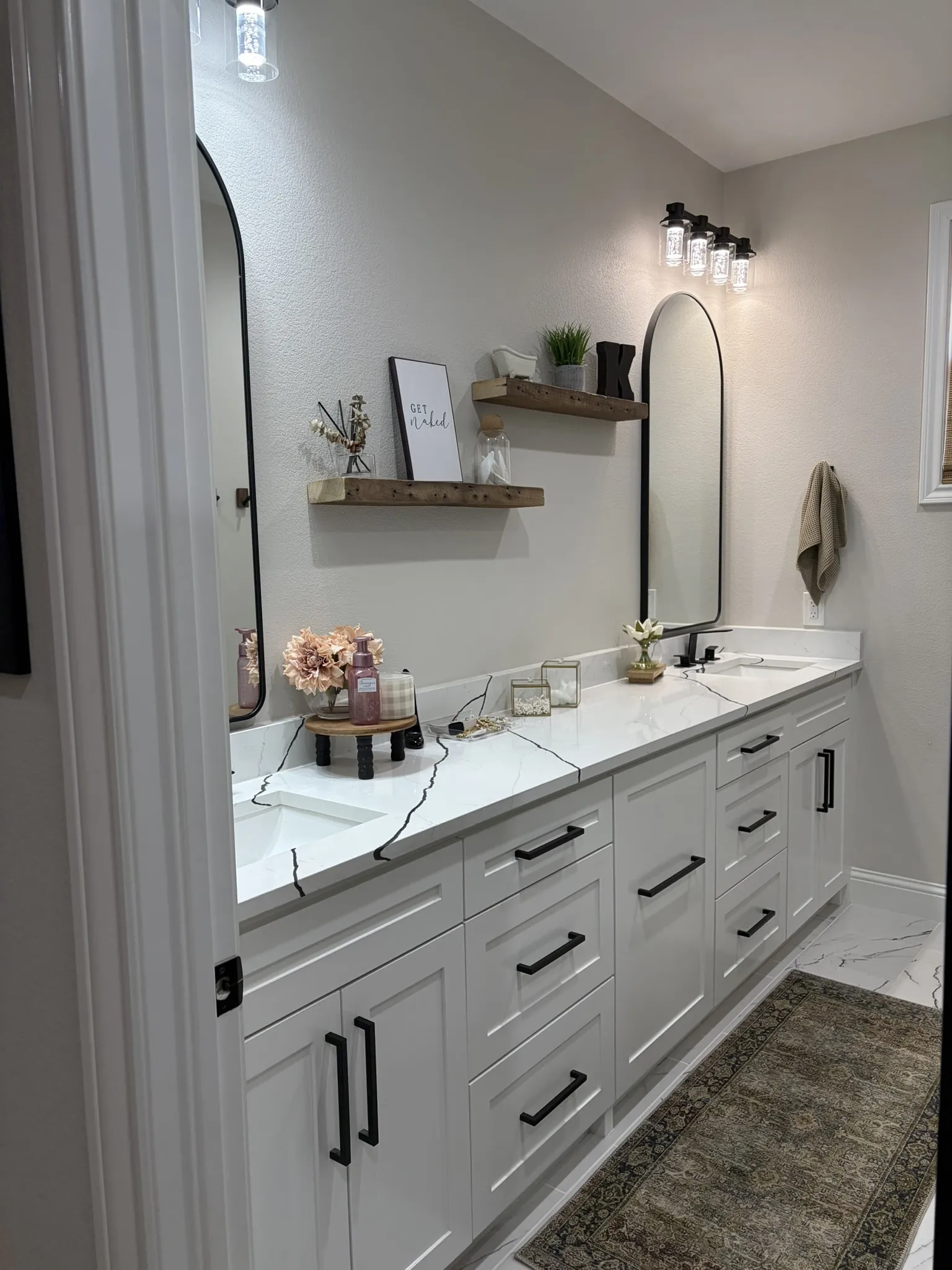 Bathroom featuring a dual vanity with white cabinetry, black hardware, and white countertops with black veining