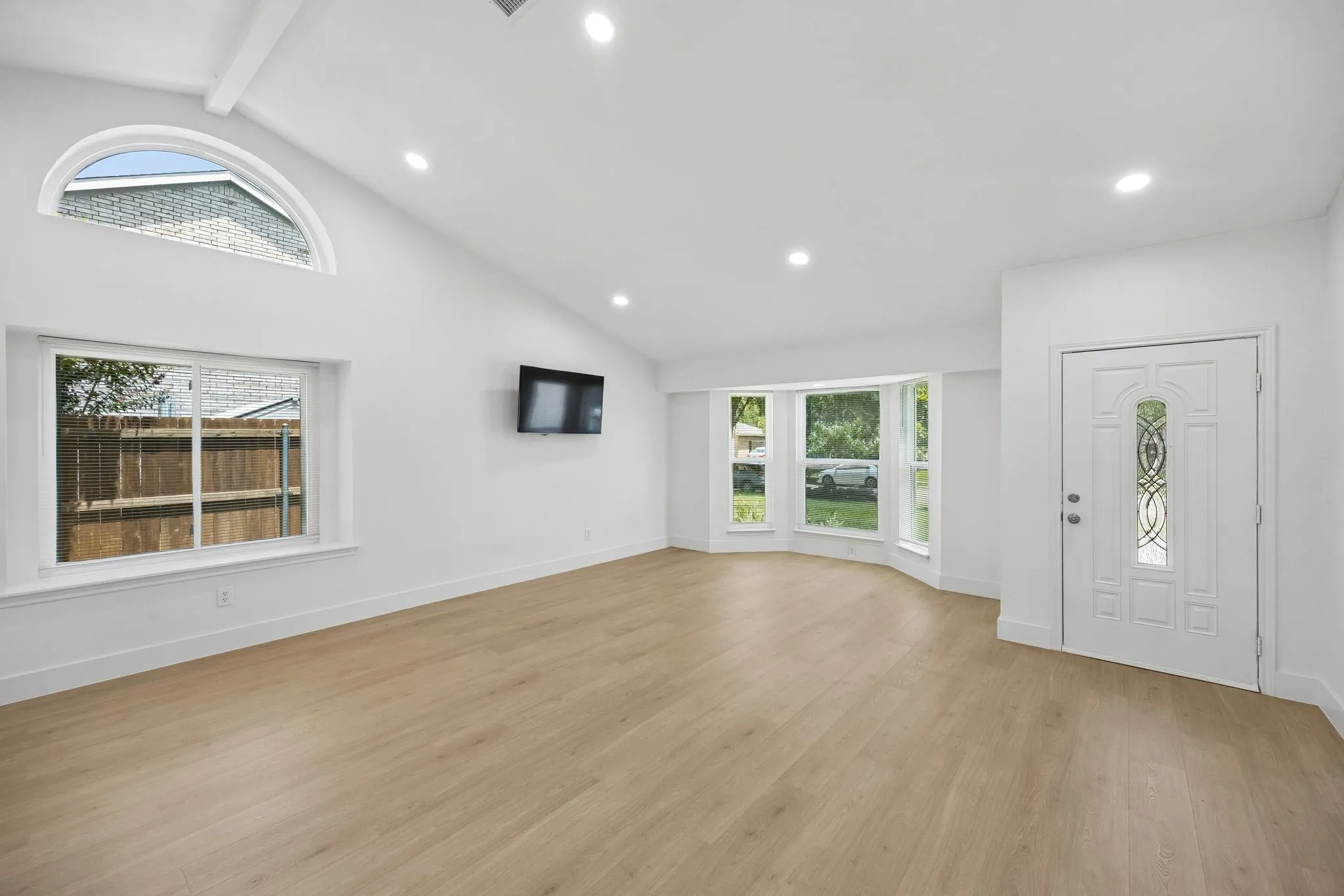 The spacious living area features dramatic vaulted ceilings, an elegant arched window, and a wall perfectly suited for entertainment.