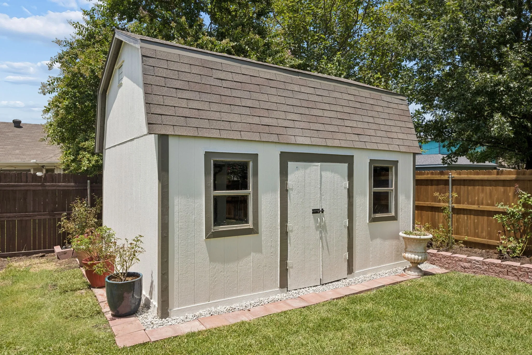 Detached storage building with windows and lofted ceiling provides excellent space for tools, hobbies, or additional storage.