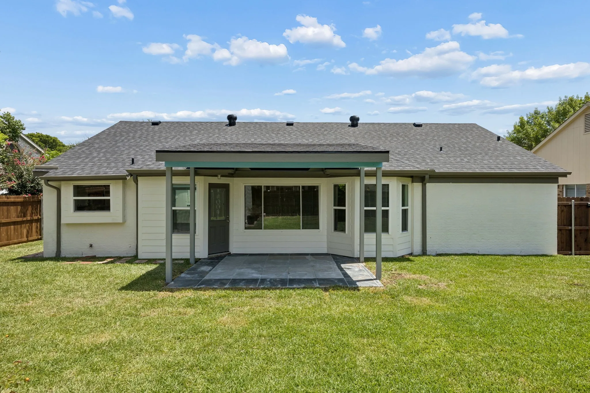 Backyard view highlighting the covered outdoor living space and well-maintained lawn—ideal for entertaining or relaxing.