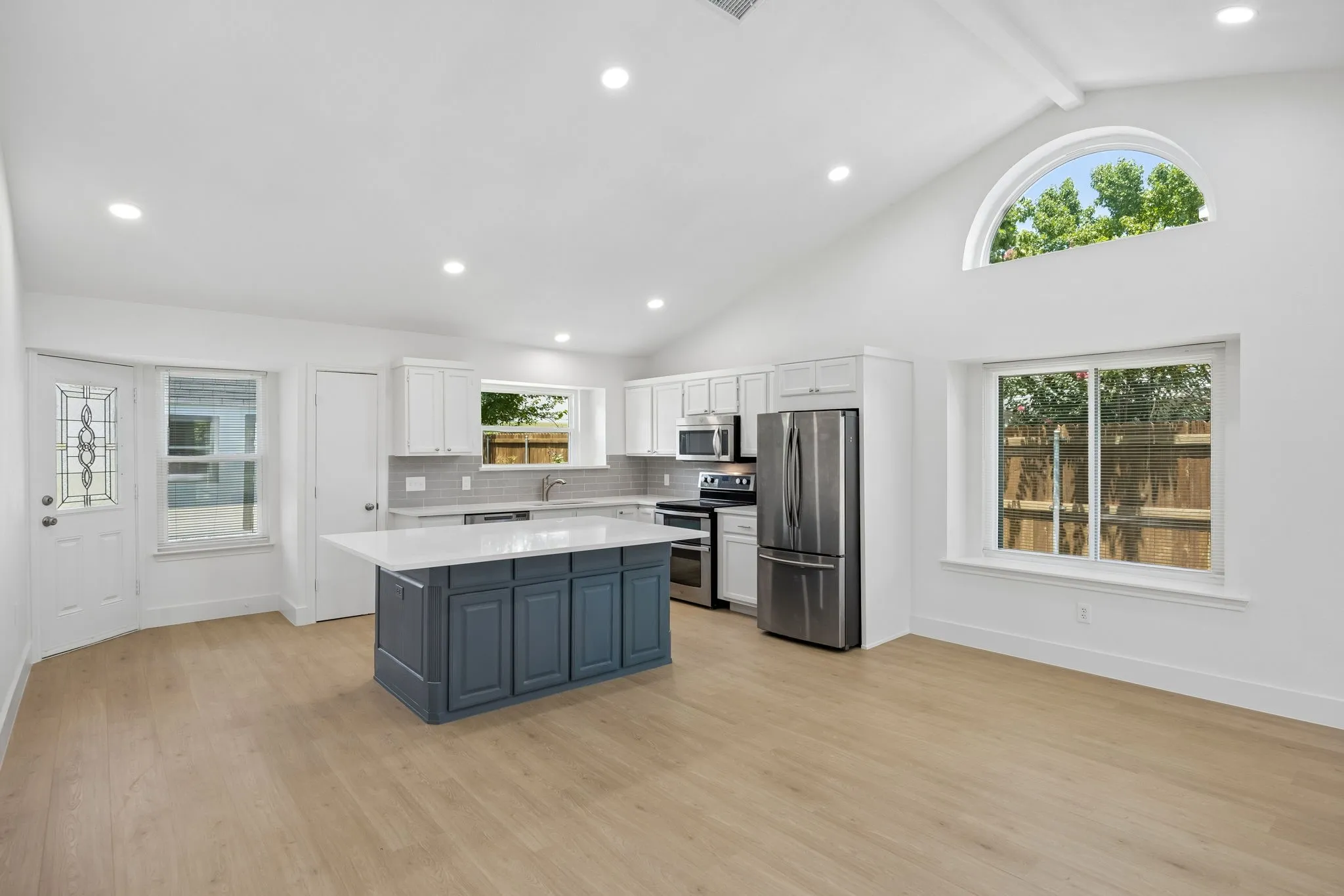 The beautifully updated kitchen features crisp white cabinetry, quartz countertops, stainless steel appliances, subway tile backsplash, and a generous center island.