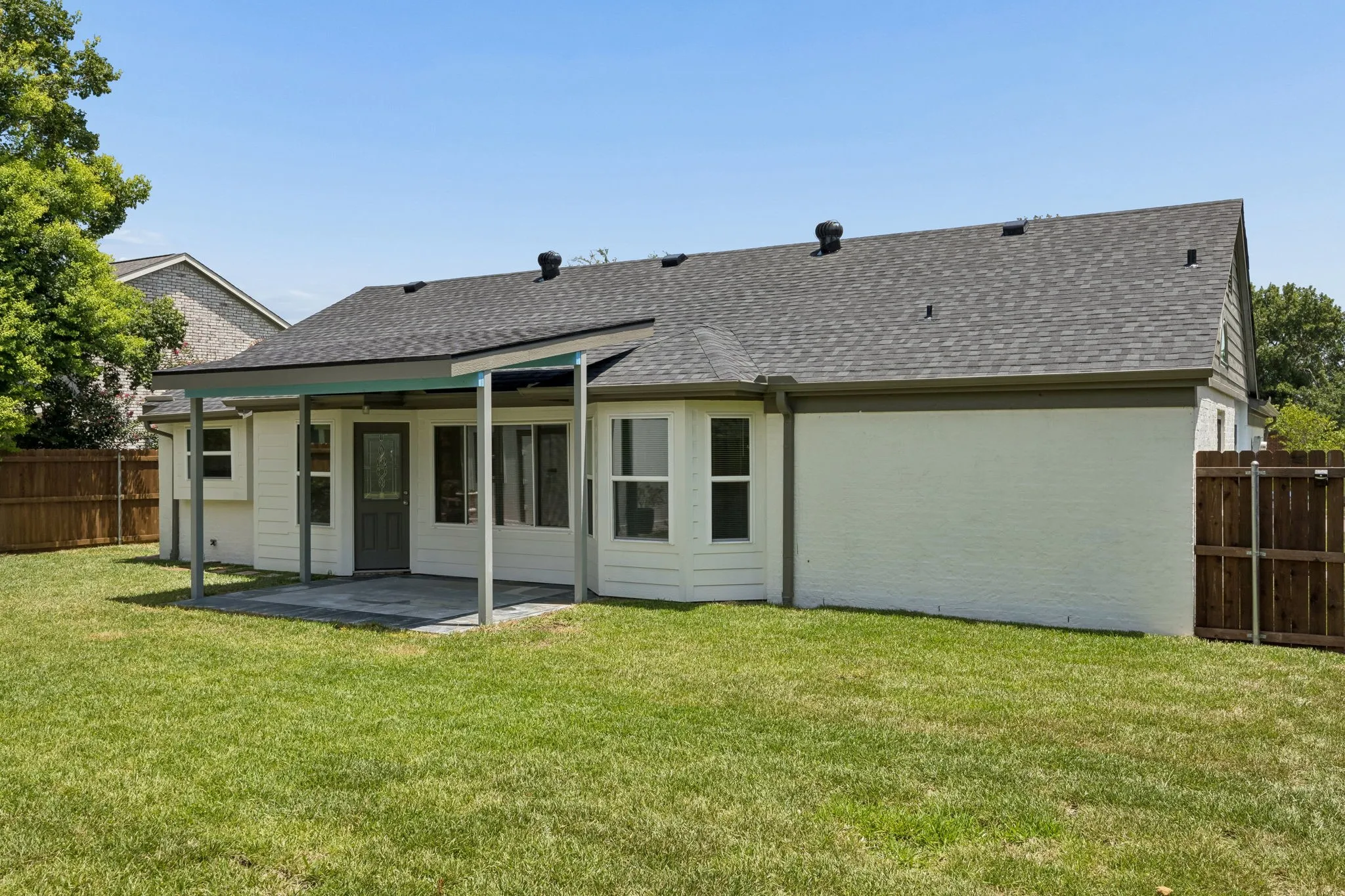 Updated rear elevation featuring a covered patio, fresh exterior finishes, and a generously sized backyard.