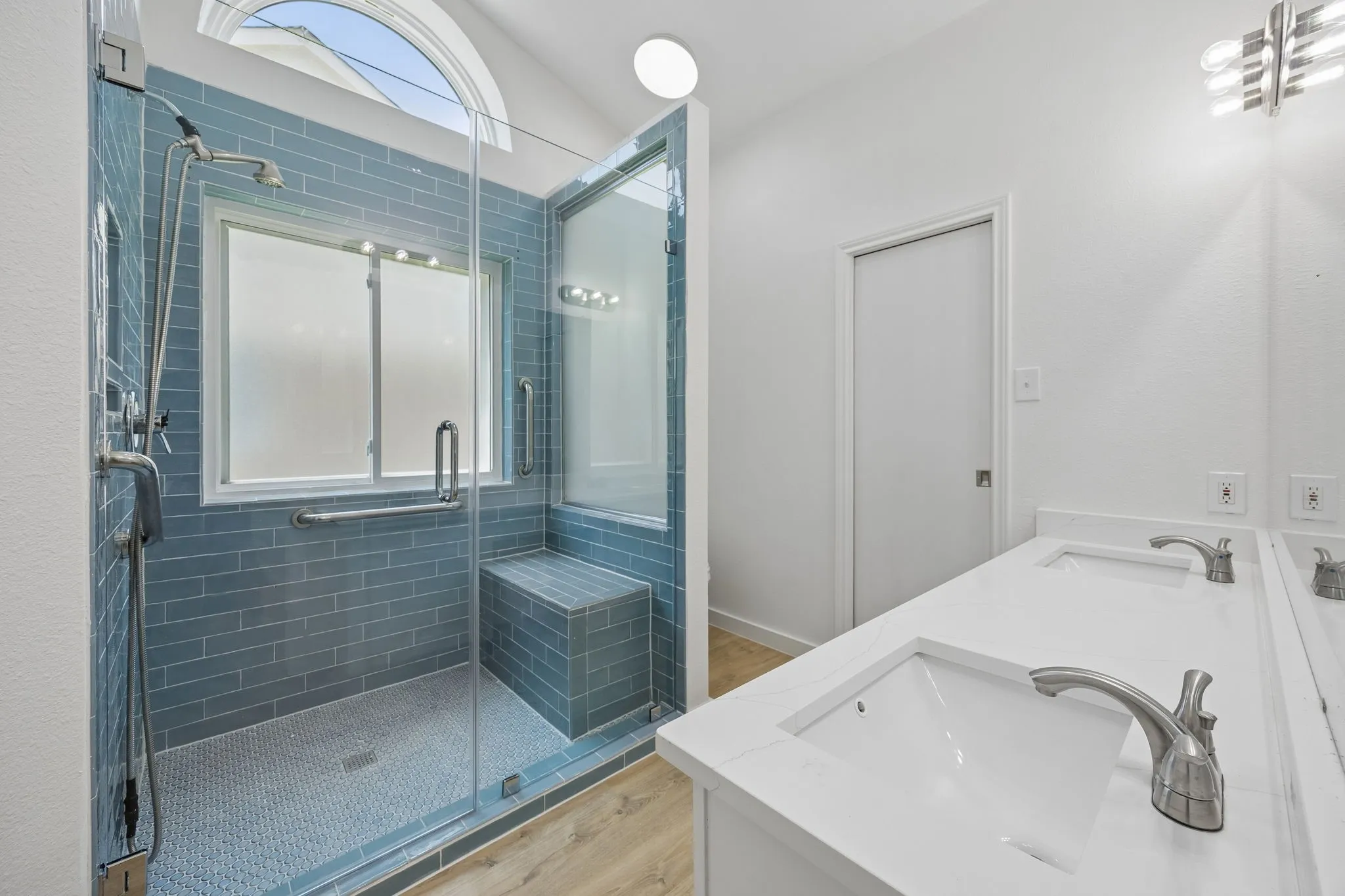 A dual-sink quartz vanity pairs perfectly with the luxurious oversized shower, offering both beauty and functionality in this thoughtfully updated retreat.