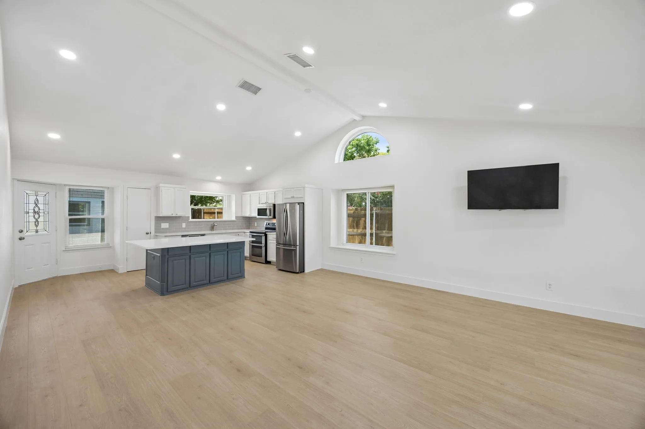 An expansive open-concept layout showcases soaring vaulted ceilings, abundant natural light, and effortless flow between the living room and kitchen.
