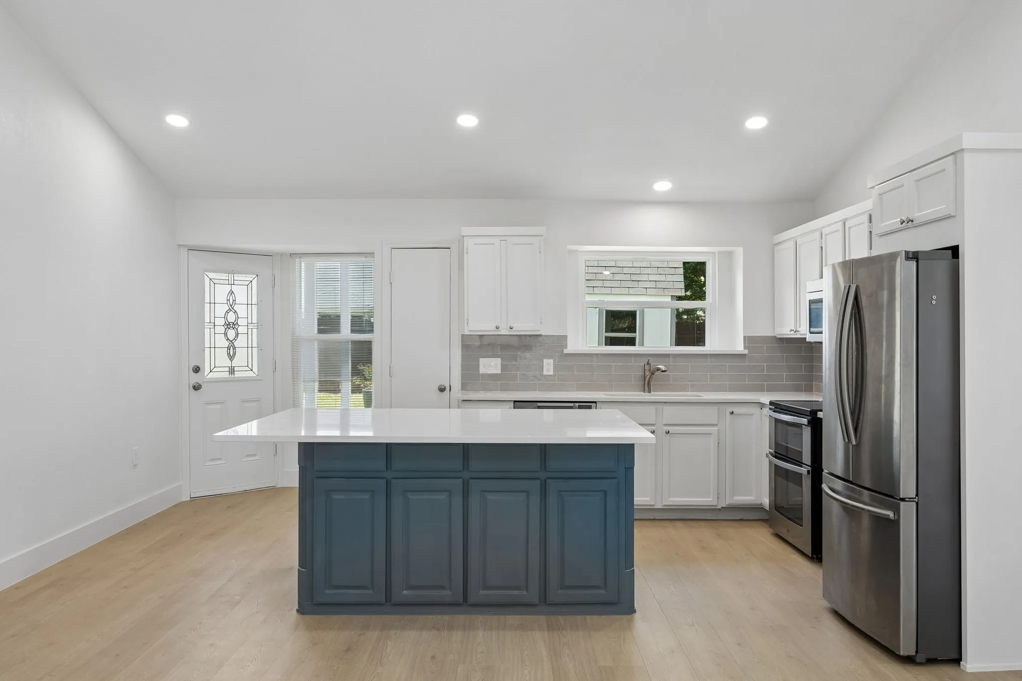 The heart of the home is this beautifully updated kitchen, where a generous quartz island, crisp white cabinetry, and stainless steel appliances create the perfect space for gathering, cooking, and entertaining.