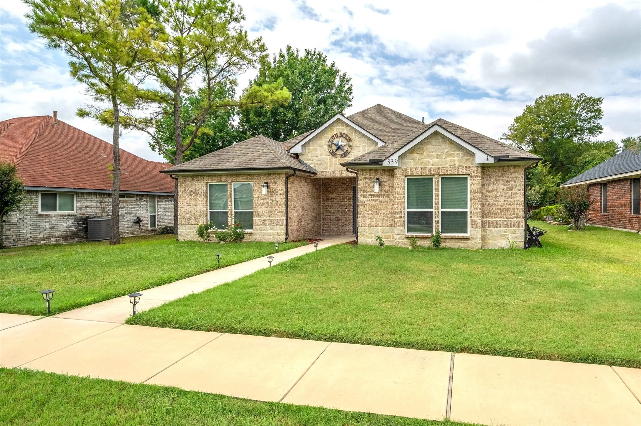 Ranch-style home featuring brick siding, roof with shingles, and a front yard