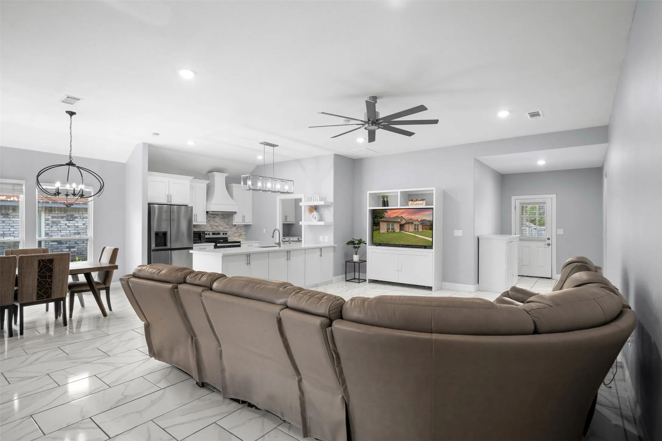 Living room with a chandelier, recessed lighting, a ceiling fan, and light marble finish floors