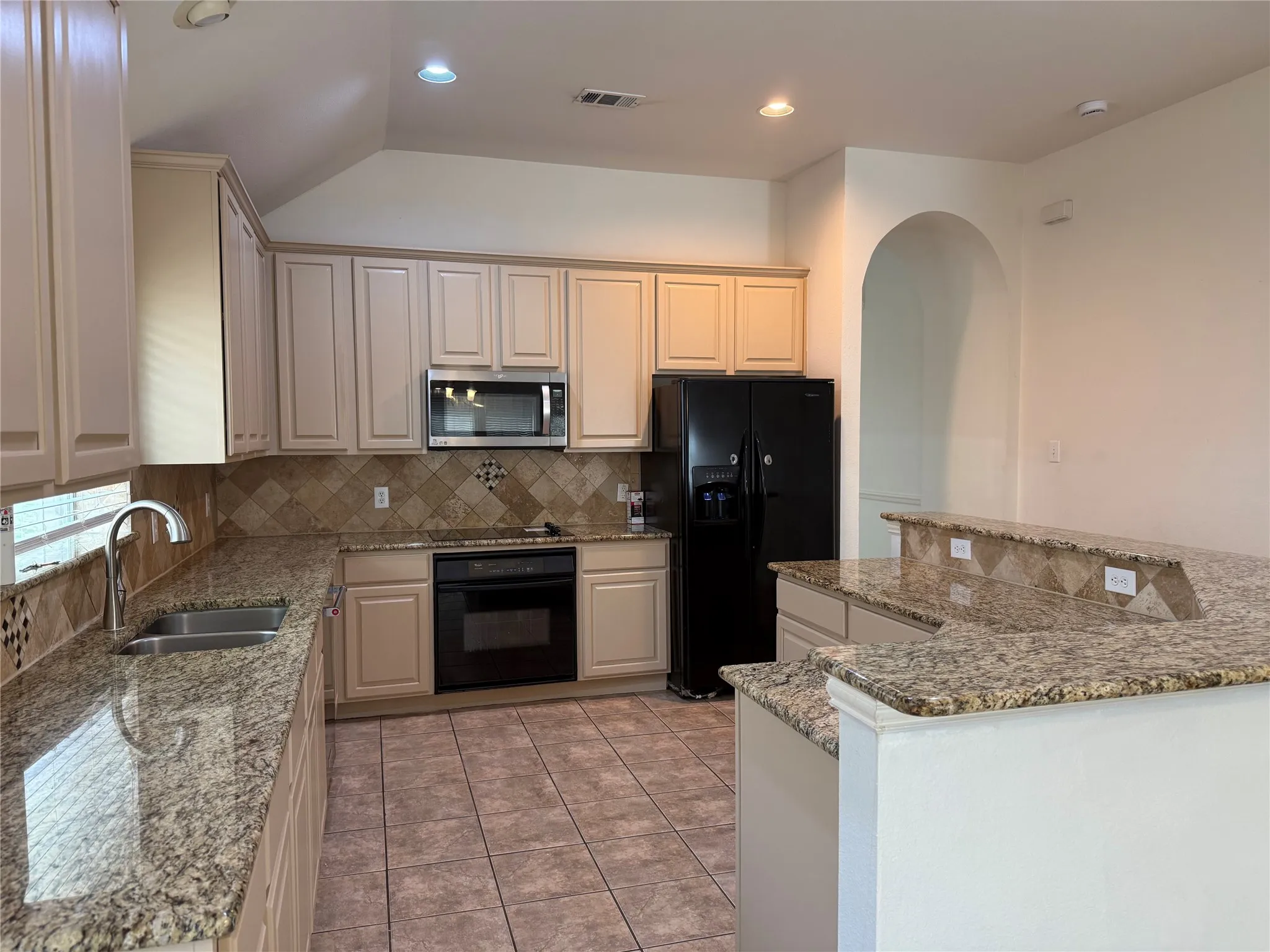 Kitchen featuring light-toned cabinetry, stainless steel appliances, granite countertops, and tile flooring