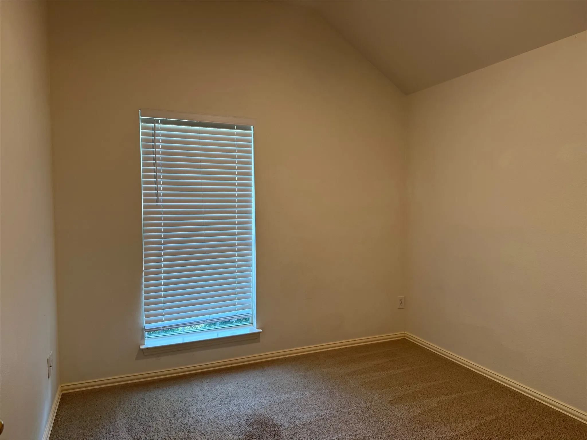 Spacious room with a single window featuring horizontal blinds