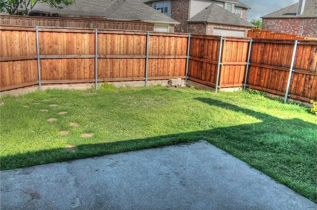 Private fenced backyard featuring a concrete patio, grassy lawn, and stepping stones