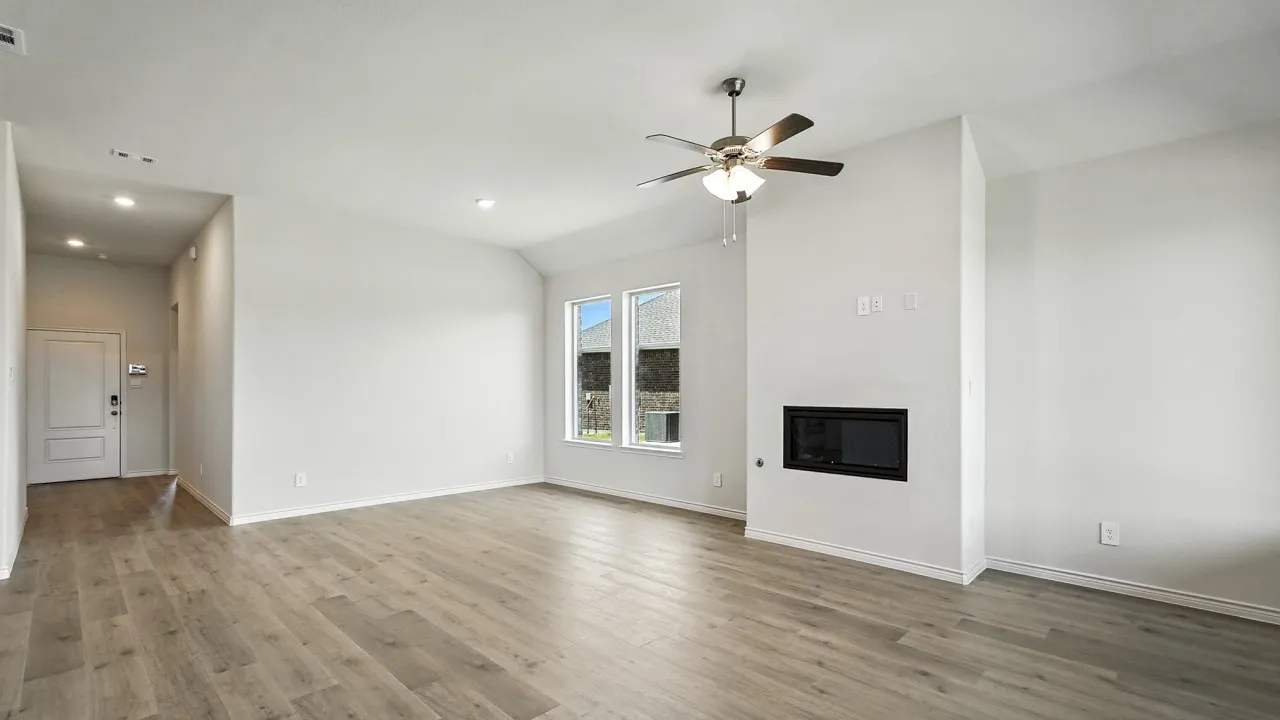 Spacious living area featuring wood-finish flooring, an integrated electric fireplace, and a ceiling fan with light fixture