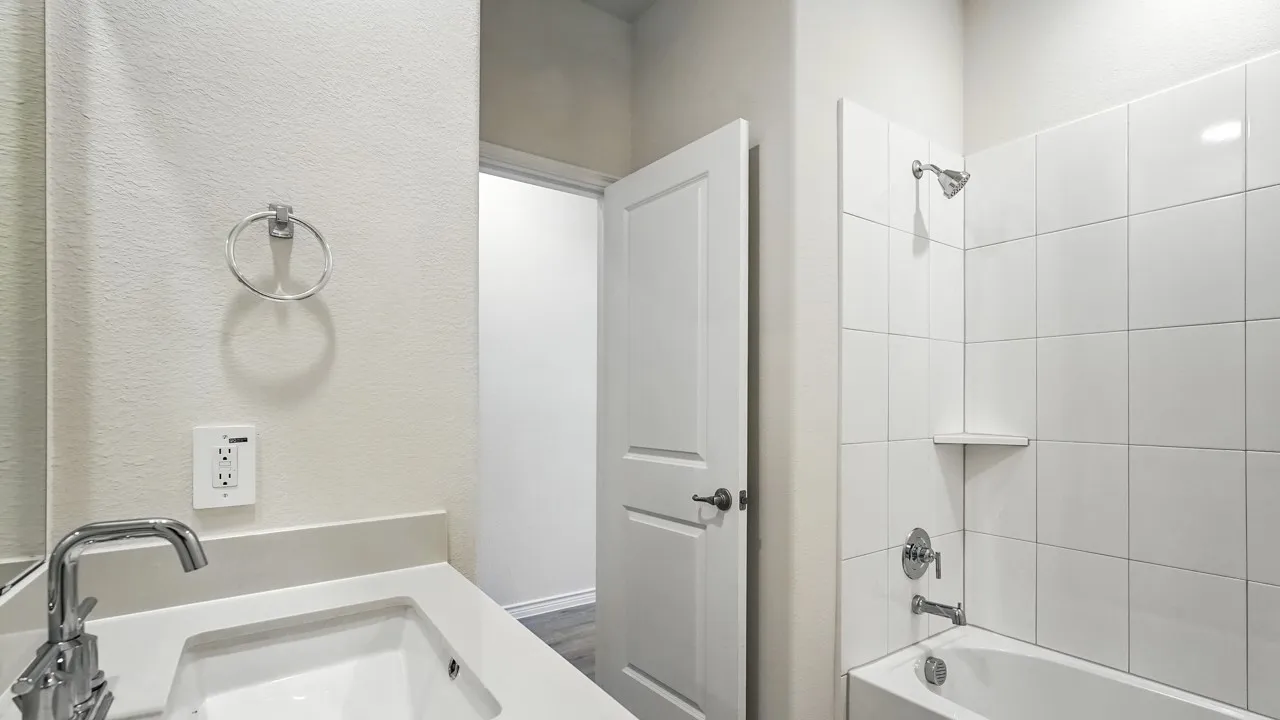Bathroom featuring a white subway tile shower, built-in tub, chrome fixtures, and a vanity with an integrated sink and light-toned countertop