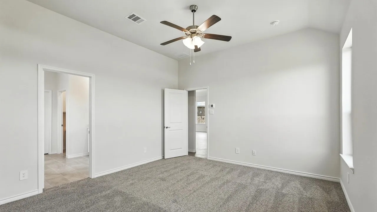 Spacious room featuring vaulted ceilings, a ceiling fan with integrated lighting, broad window, and plush carpeting