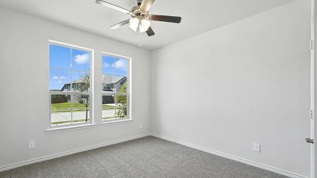 Room with twin pane windows, neutral grey carpet, white walls, and a ceiling fan with light fixture