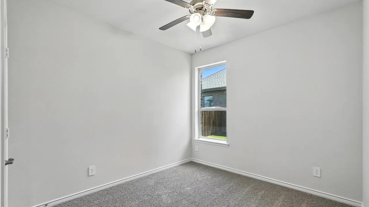 Neutral-toned room with plush carpeting, a single window, white trim, and a ceiling fan