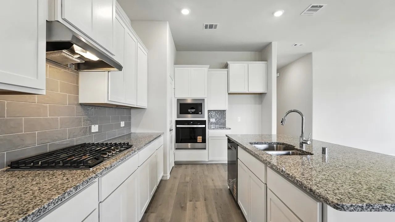 Contemporary kitchen featuring white cabinetry, granite countertops, a gas cooktop, built-in oven and microwave, and wood-finish flooring