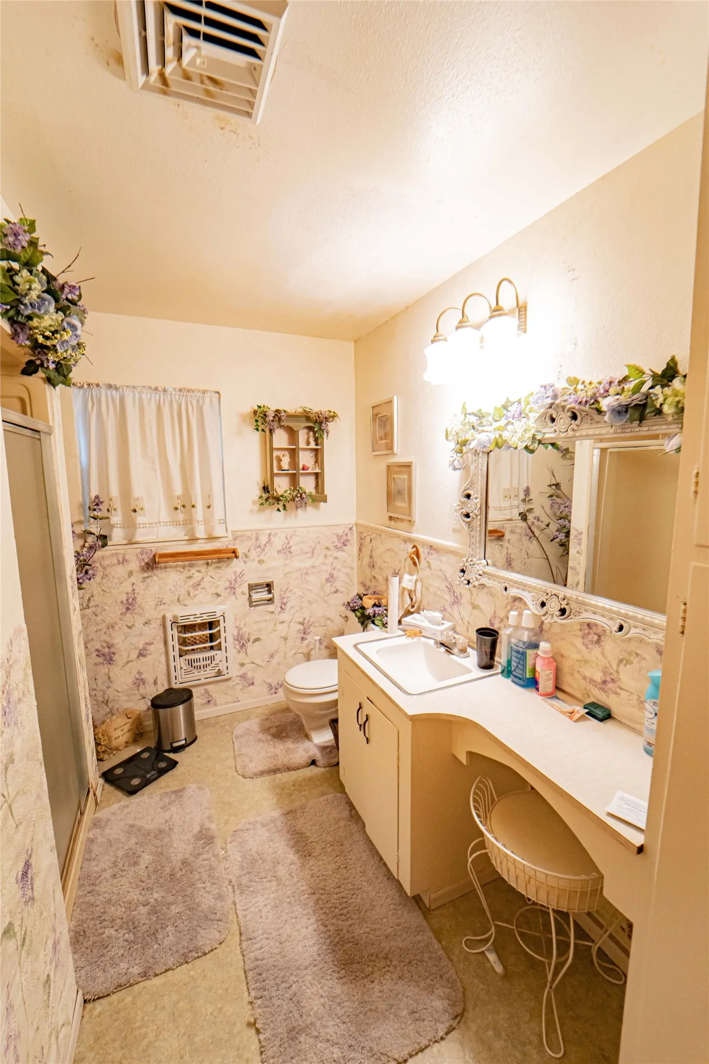 Bathroom featuring a single vanity with an integrated sink, an extended countertop, and a wall-mounted light fixture