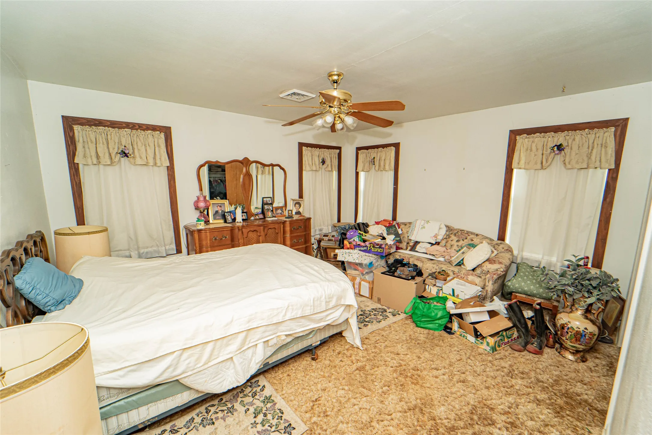 Carpeted interior space featuring white walls and a ceiling fan