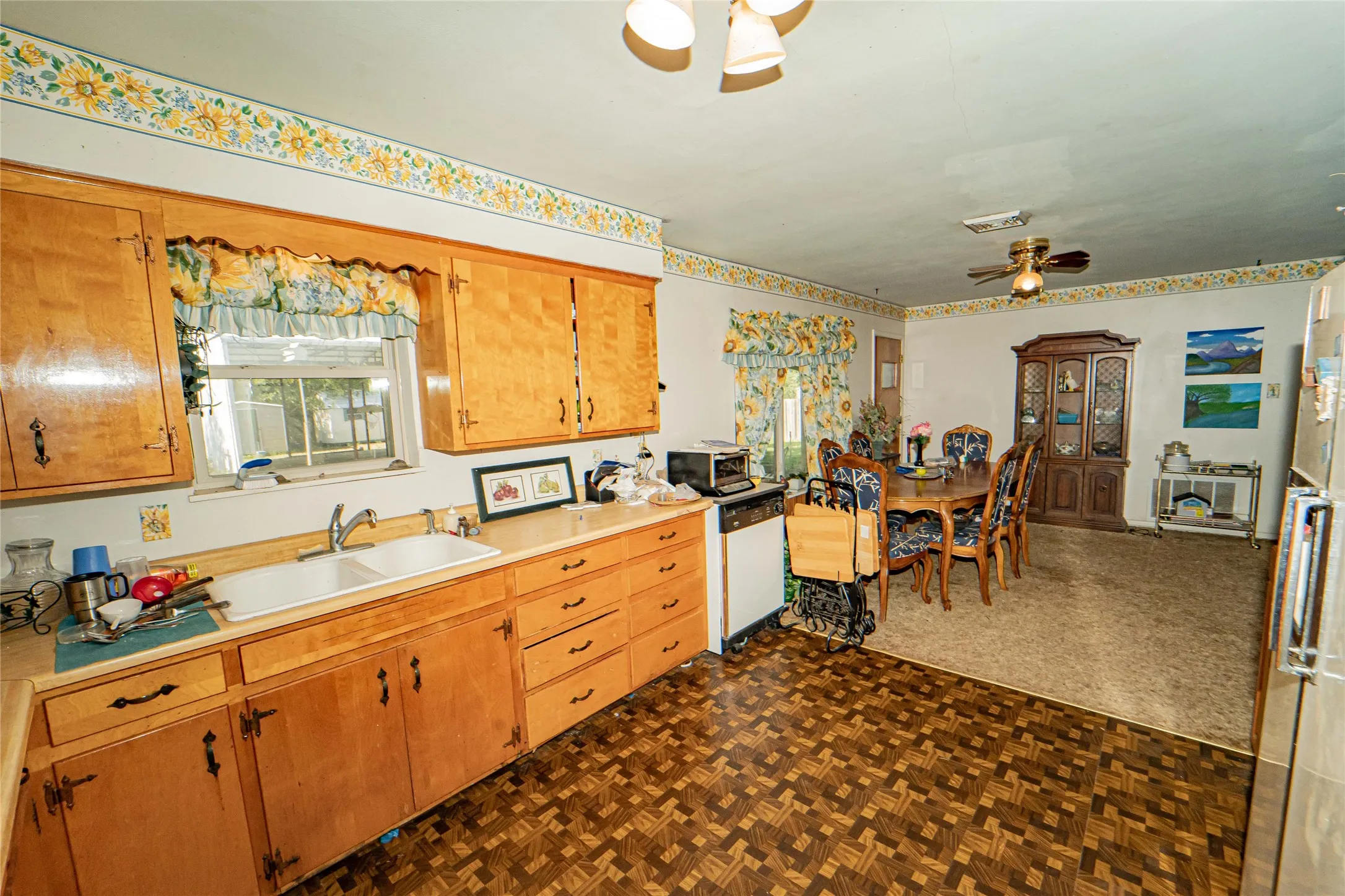 Kitchen and dining area featuring wood-finish cabinetry, a double basin sink, and patterned flooring