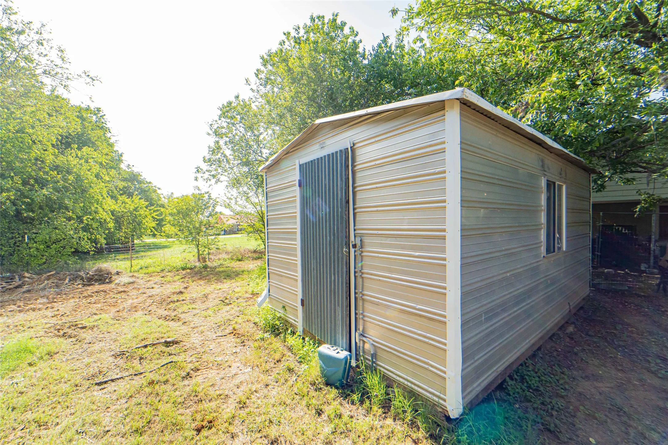 Metal storage shed featuring a corrugated metal door and a single window