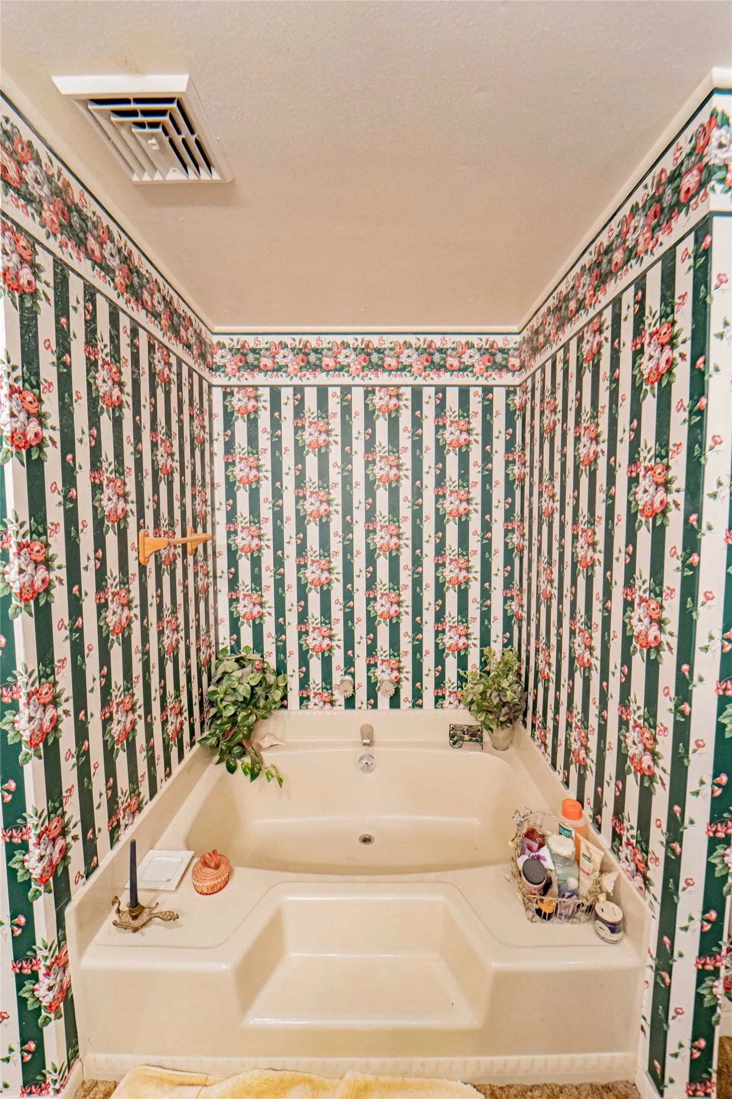 Built-in soaking tub with integrated steps, surrounded by floral and striped wallpaper with a coordinating border