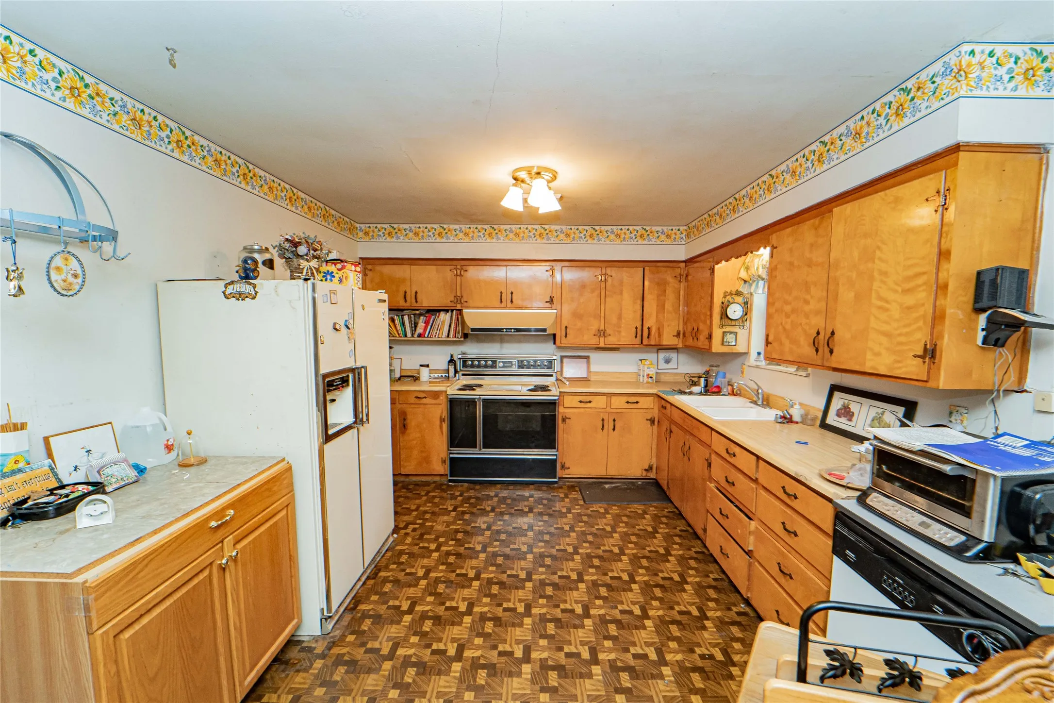 Kitchen featuring extensive wood cabinetry, laminate countertops, a double basin sink, and patterned flooring