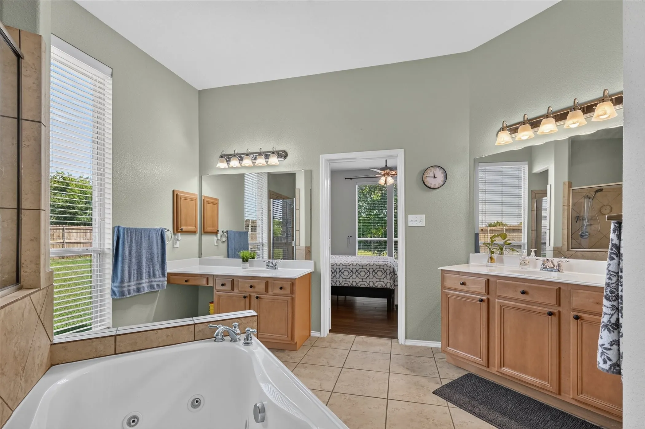 Bathroom featuring a built-in jetted tub, dual vanity with wood cabinetry, and tiled flooring