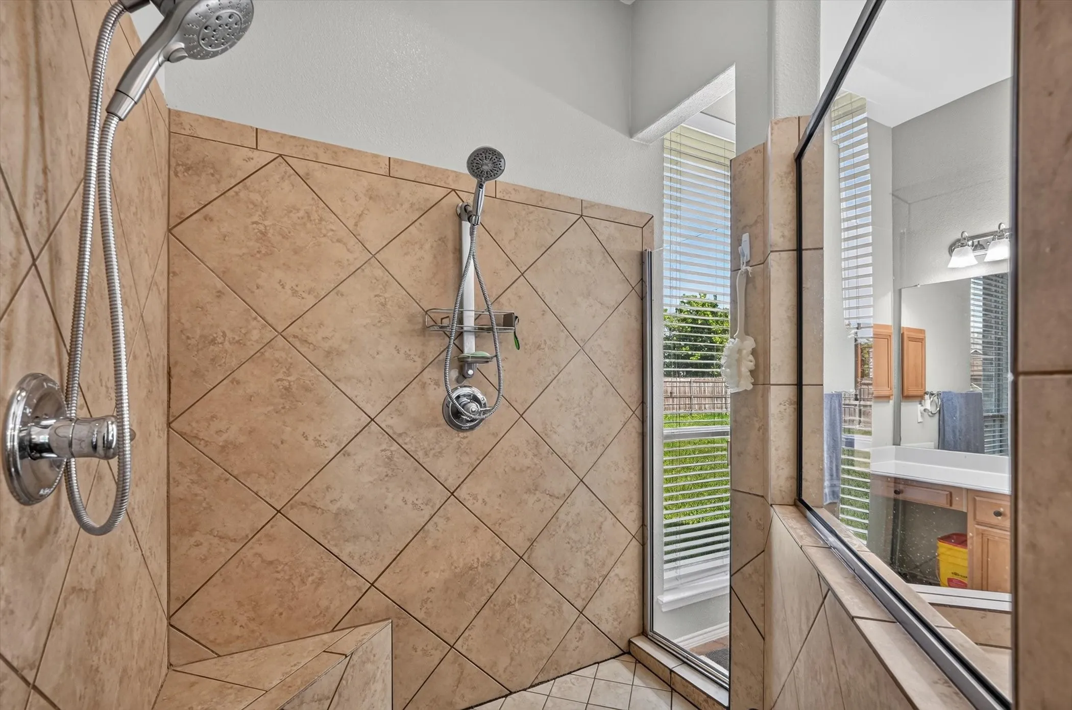 Tiled shower enclosure featuring dual shower heads, a built-in bench, and a glass partition with a window