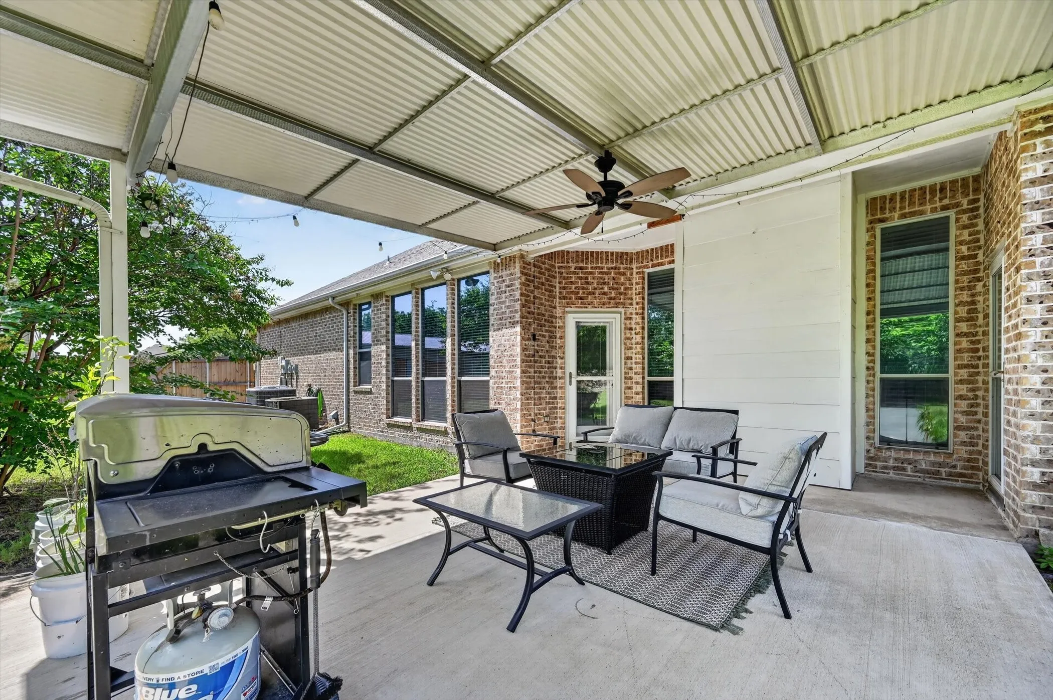 Covered patio featuring a corrugated metal roof, concrete flooring, and a ceiling fan
