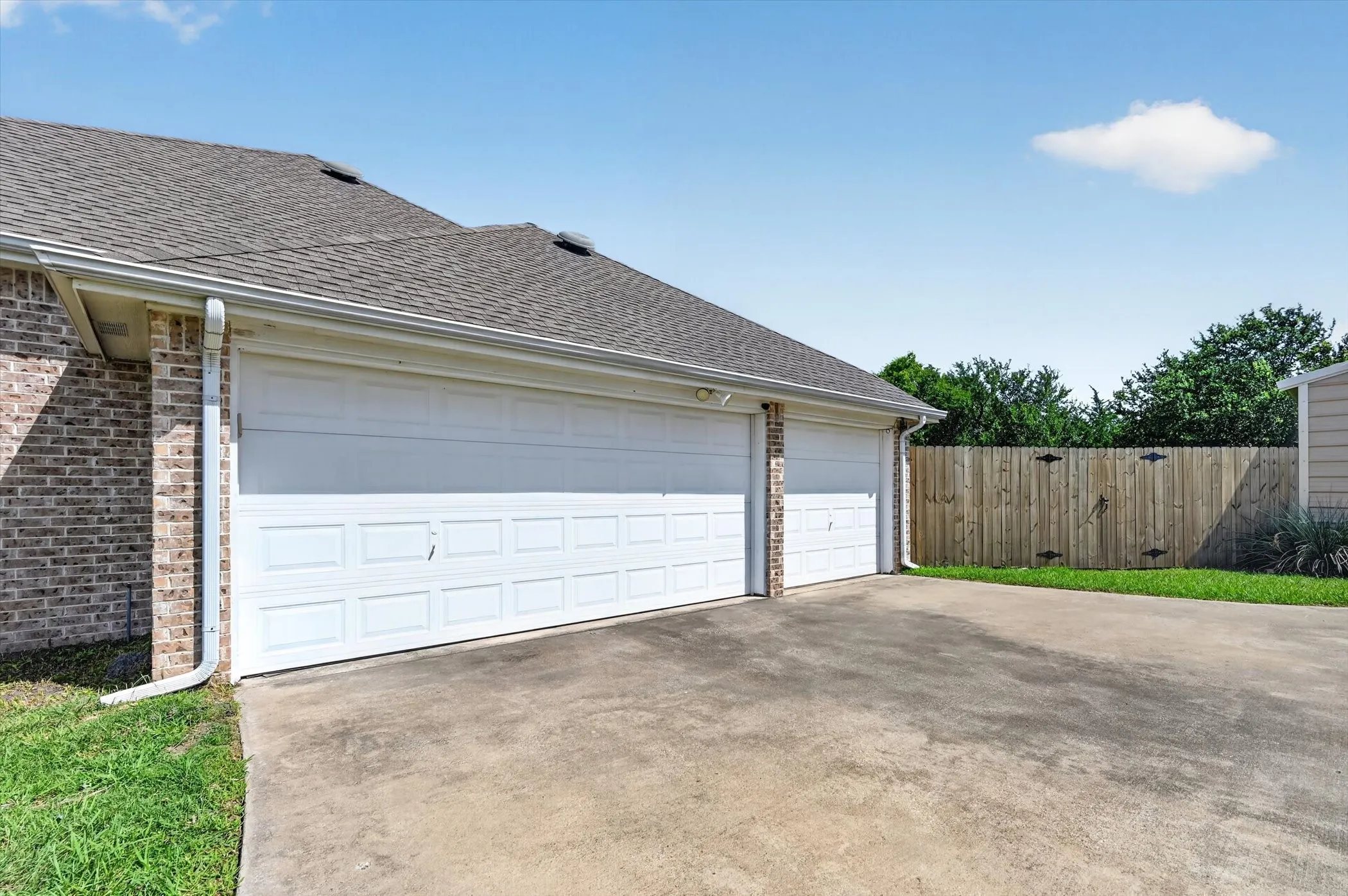 Two white panel garage doors with a concrete driveway