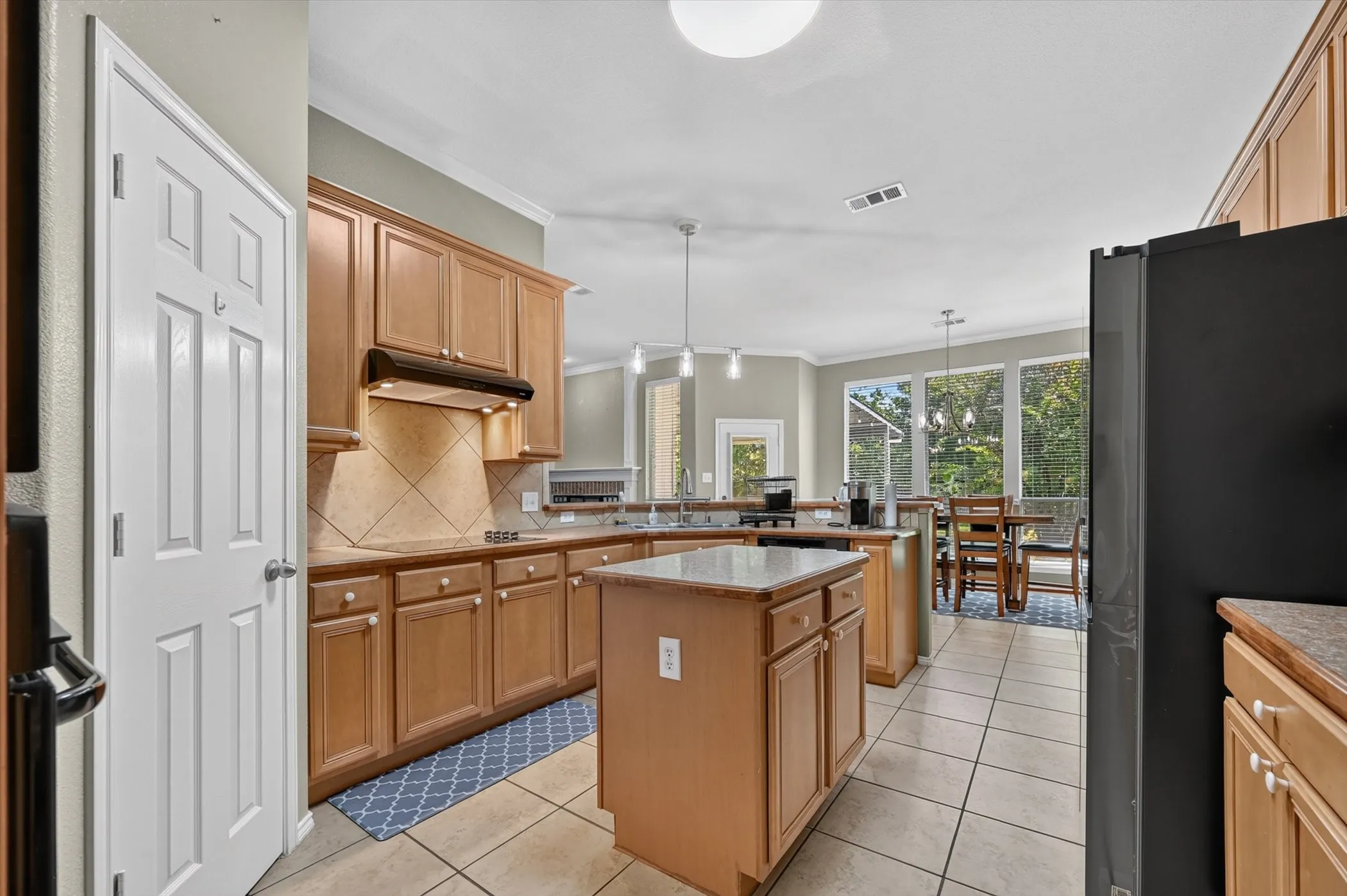 Kitchen featuring light wood cabinetry, a central island with a solid surface countertop, and large rear-facing windows