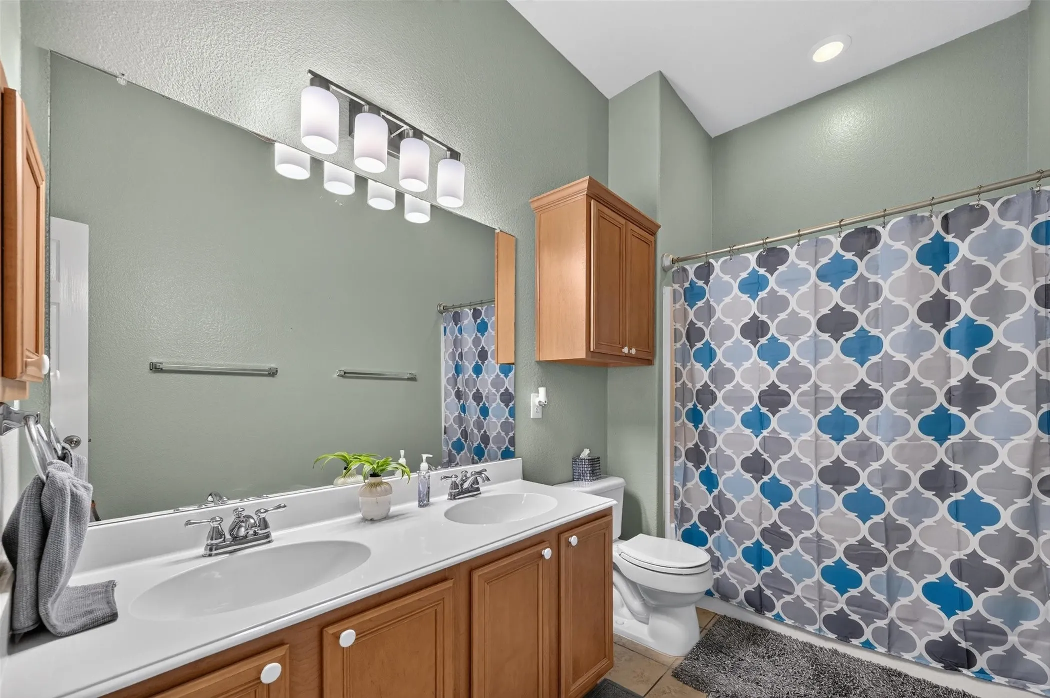 Double vanity with integrated sinks, chrome faucets, and wood-finish cabinetry