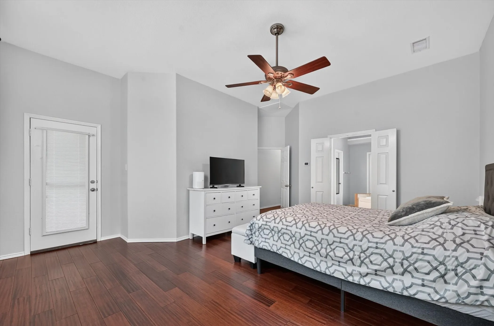 Spacious room featuring rich wood-finish flooring and a vaulted ceiling