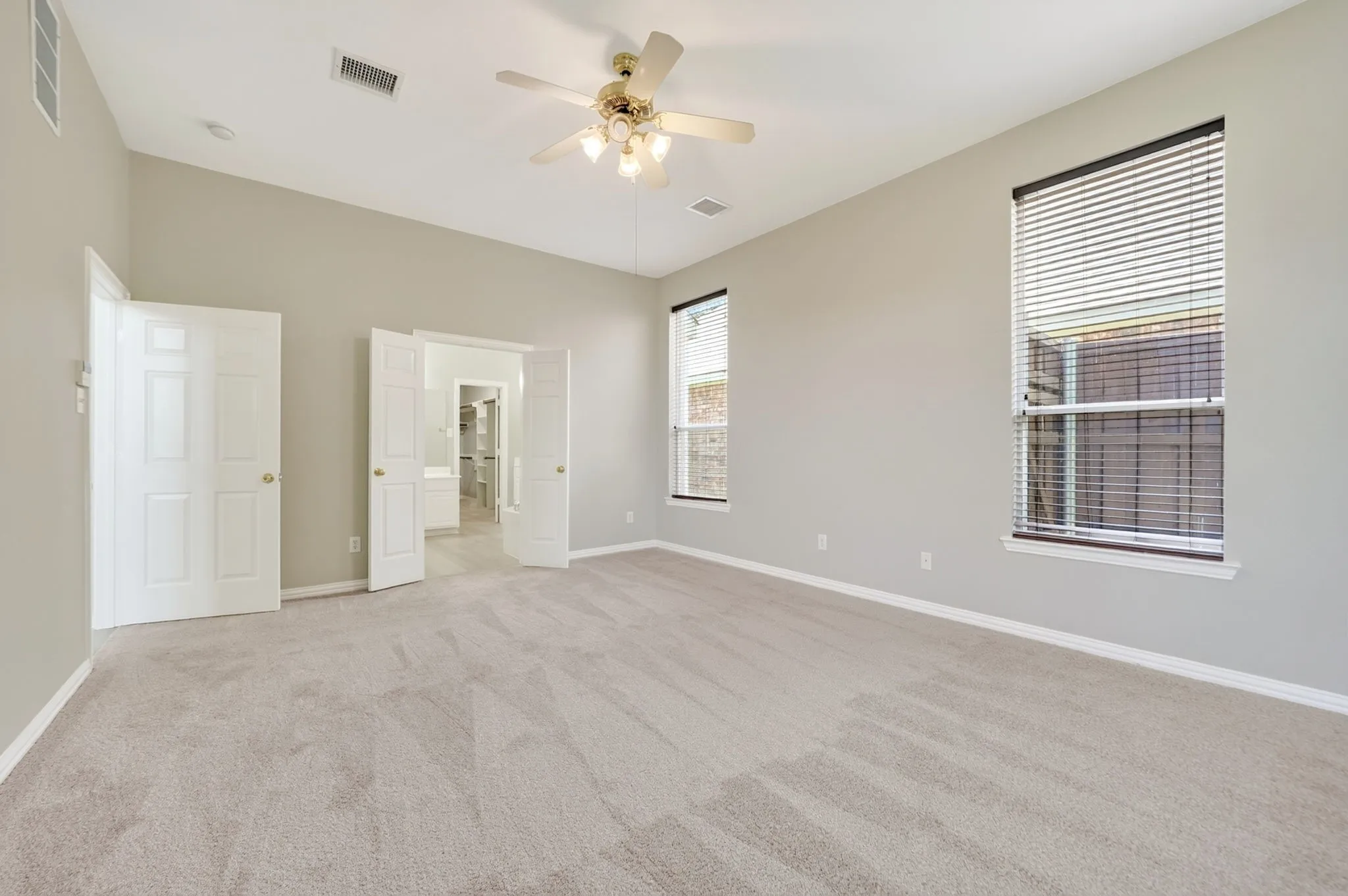 Primary suite with multiple windows and ceiling fan