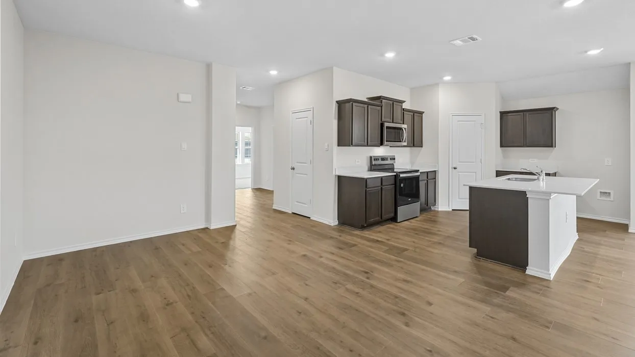 Open-concept living space featuring wood-finish flooring, recessed lighting, and a kitchen with dark wood cabinetry