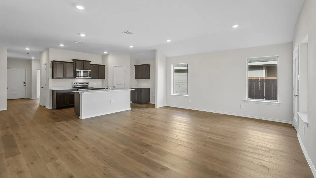Open-concept living area featuring wood-finish flooring, recessed lighting, and multiple windows