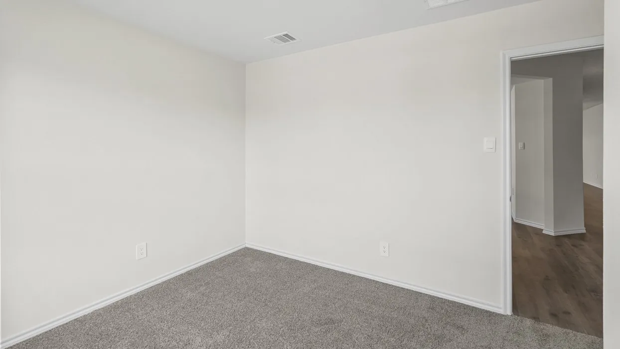 Interior room featuring light gray carpeting, white baseboards, and neutral wall paint