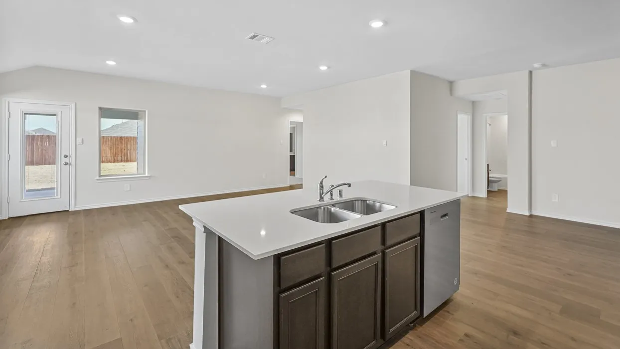 Kitchen island featuring a double-basin stainless steel sink with a high-arc faucet, integrated dishwasher, and white countertop