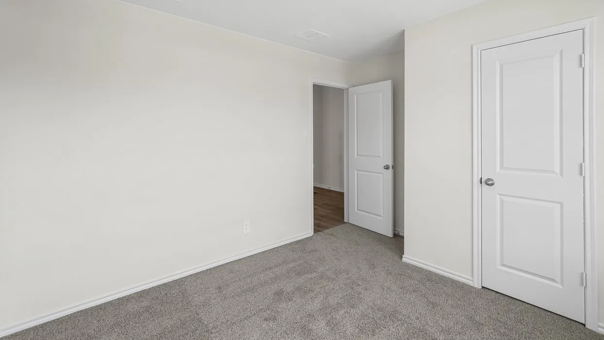Neutral-toned room featuring gray carpeting, white baseboards, and two white two-panel doors with brushed nickel hardware